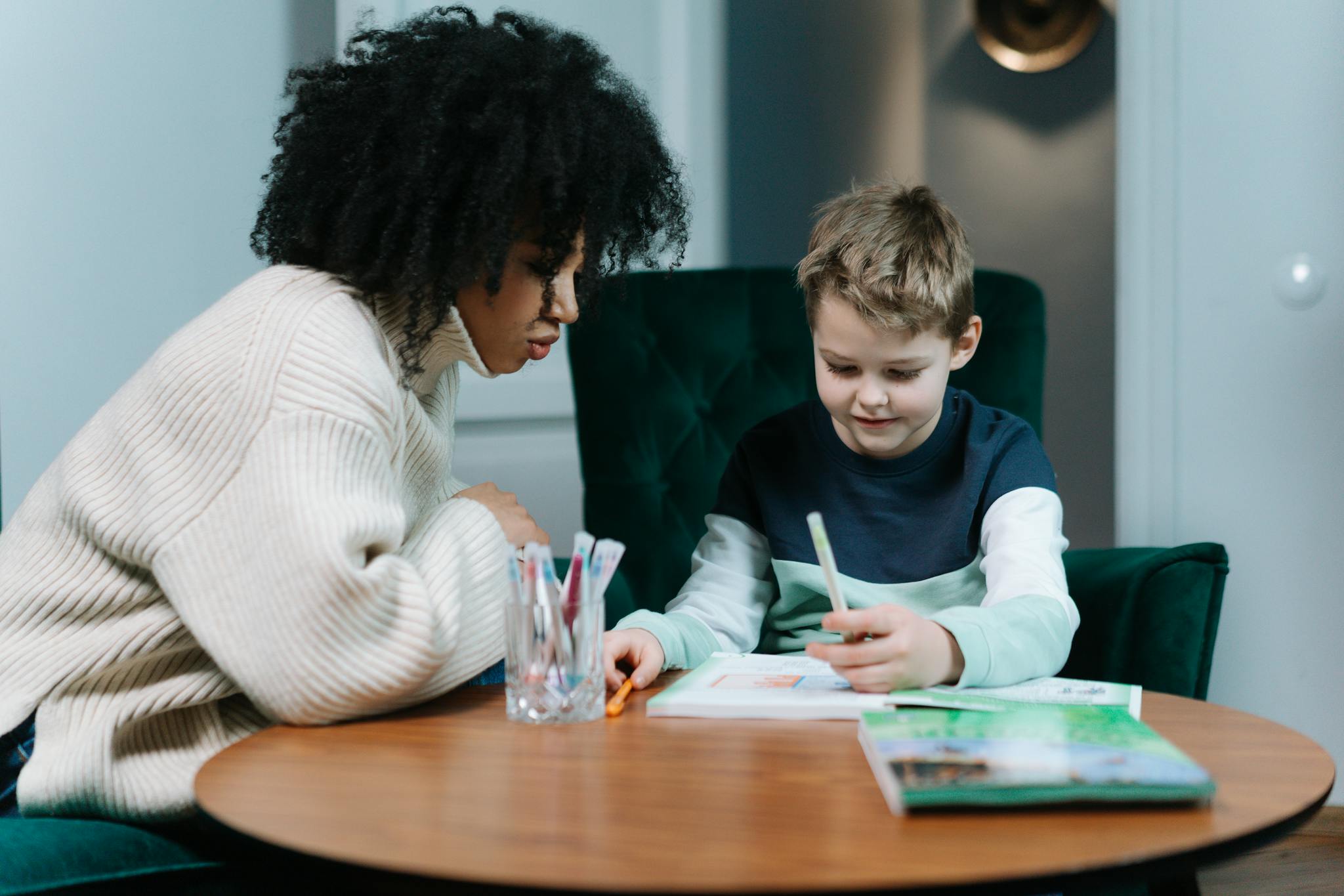 A child and tutor engaged in an educational activity at a cozy indoor setting.