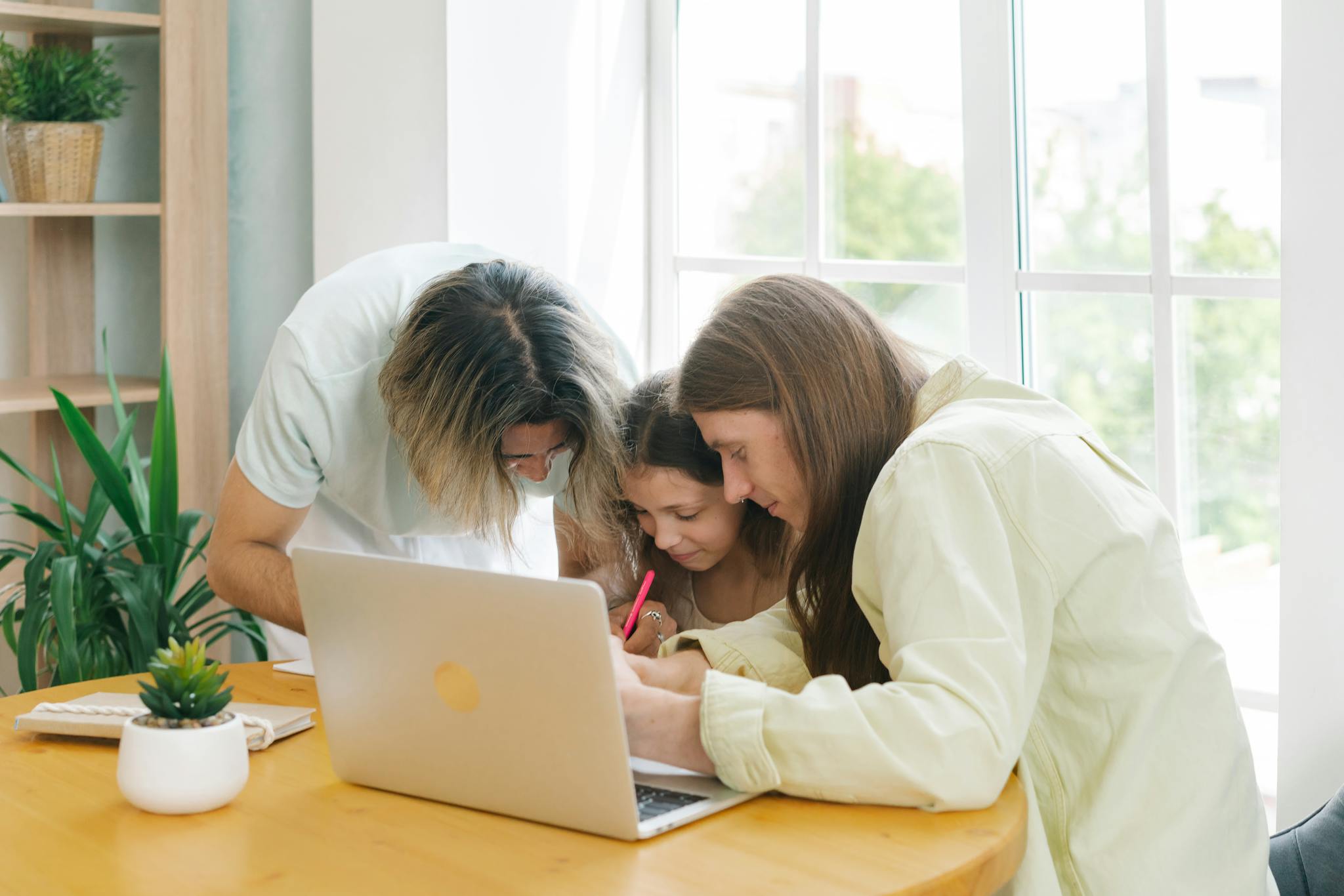 Parents helping their child with homework while sitting together at a table.