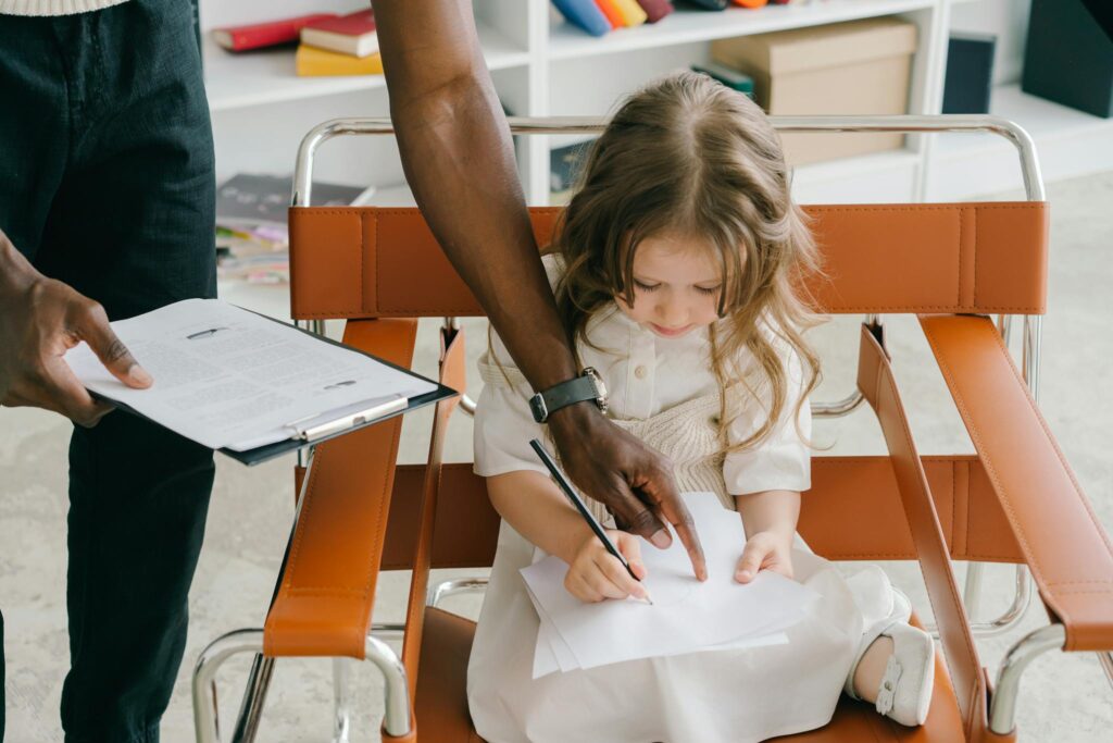 Young girl being guided by tutor while writing, emphasizing focused education.